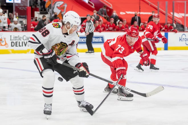 Detroit left wing Adam Erne tries to steal the puck away from Chicago right wing Patrick Kane in the first period.