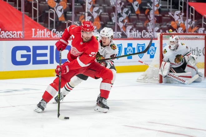 Detroit center Dylan Larkin keeps the puck away from Chicago defenseman Wyatt Kalynuk in the third period during a game between the Detroit Red Wings and the Chicago Blackhawks, at Little Caesars Arena, in Detroit, April 15, 2021.
