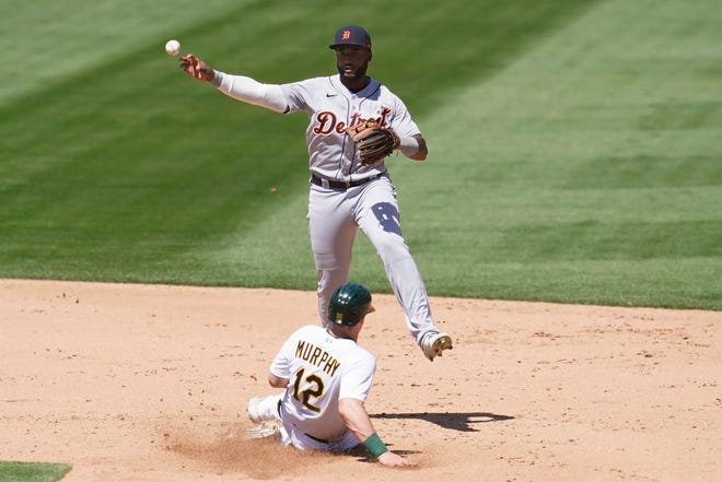 Tigers second baseman Niko Goodrum, top, throws to first base after forcing out the Athletics' Sean Murphy (12) on a double play hit into by Aramis Garcia during the fifth inning.