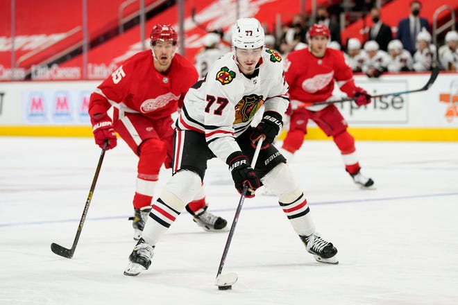 Chicago Blackhawks center Kirby Dach (77) controls the puck ahead of Detroit Red Wings defenseman Danny DeKeyser (65) during the third period of an NHL hockey game, Saturday, April 17, 2021, in Detroit.