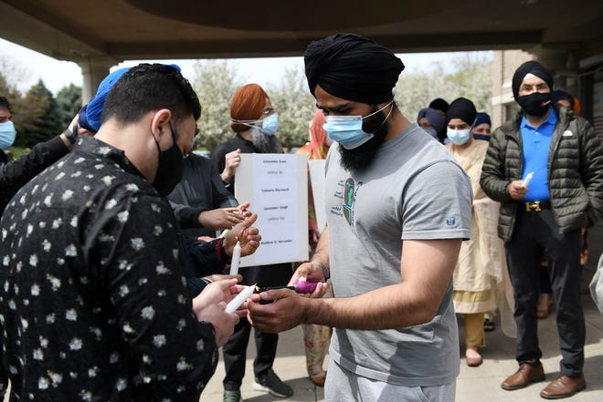 Jaswant Singh, left, 34, of Lansing has his candle lit by Amandeep Jhajj, 30, of Canton at a Sikh solidarity vigil at Plymouth Gurdwara Sahib in Plymouth, Michigan, on Sunday, April 18, 2021. People from the Sikh community and others gathered to remember the eight people killed Thursay at an Indianapolis Federal Express facility, which included four Sikhs, and to speak out against gun violence.