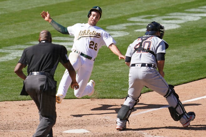 Oakland Athletics' Matt Olson (28) slides into home to score against Detroit Tigers catcher Wilson Ramos, right, during the ninth inning.