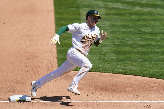 The Athletics' Mark Canha rounds third base to score against the Tigers during the fourth inning.
