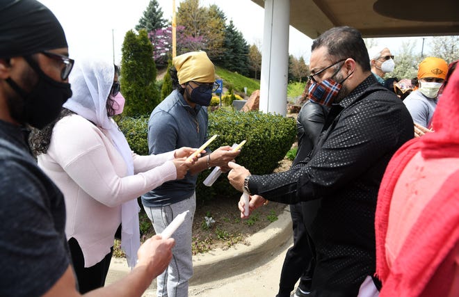 Ramandeep Sidhu, left, 54, of South Lyon, Amisha Datta, 22, and her brother, Aniketh Datta, 18, both of Novi have their candles lit by Gurjinder Singh, 52, of Lansing.