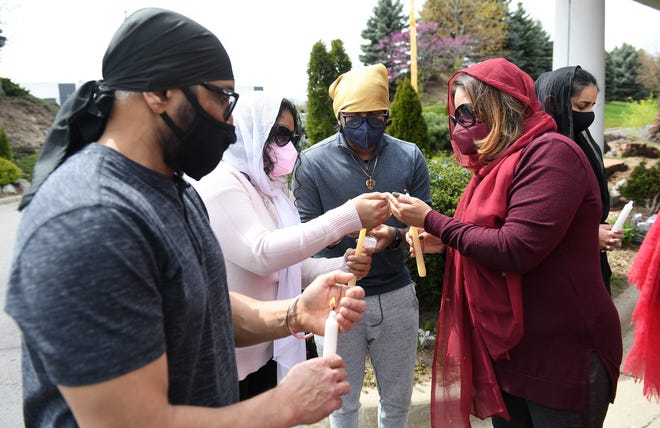 Ramandeep Sidhu, left, 54, of South Lyon watches as Amisha Datta, 22, and her brother, Aniketh Datta, 18, have their candles lit by their mother, Somlika Datta, 48, of Novi.