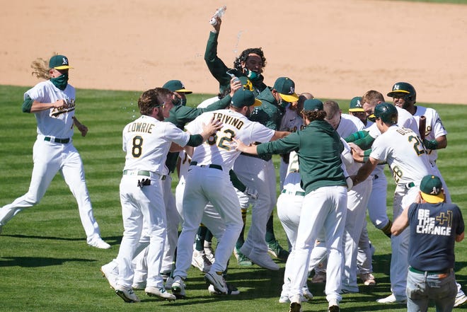Oakland Athletics' Mitch Moreland (obscured) is congratulated by teammates after hitting into an error that scored Matt Olson for the winning run during the ninth inning.