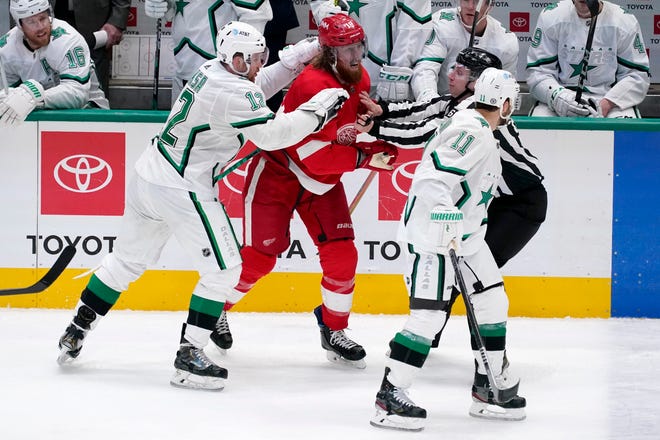 Dallas Stars' Radek Faksa (12) and linesman Libor Suchanek, right rear, hold back Detroit Red Wings defenseman Marc Staal who attempts to reach center Andrew Cogliano (11) as he skates past in the second period of an NHL hockey game in Dallas, Tuesday, April 20, 2021.