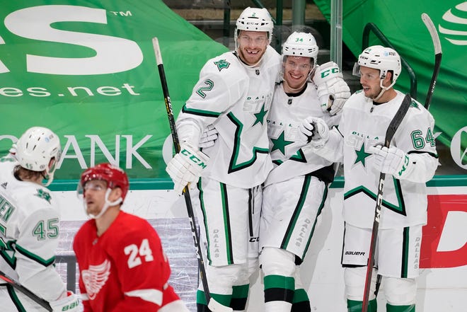 Detroit Red Wings right wing Richard Panik (24) skates past as Dallas Stars' Sami Vatanen (45), Jamie Oleksiak (2), Denis Gurianov (34) and Tanner Kero (64) celebrate a goal scored by Oleksiak in the second period of an NHL hockey game in Dallas, Tuesday, April 20, 2021.