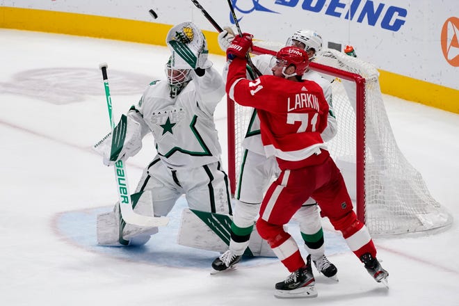 Dallas Stars goaltender Jake Oettinger (29) attempts to glove a shot as defenseman John Klingberg, center, helps against pressure from Detroit Red Wings center Dylan Larkin (71) in the third period of an NHL hockey game in Dallas, Tuesday, April 20, 2021.