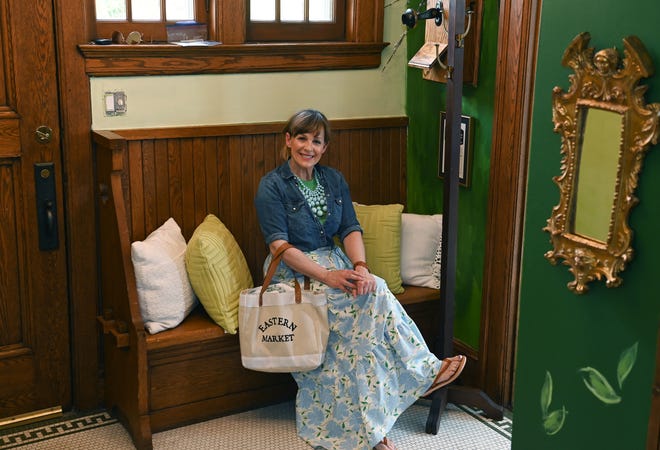 Cindy sits on the foyer’s original bench, the same spot where early telephone customers once waited.