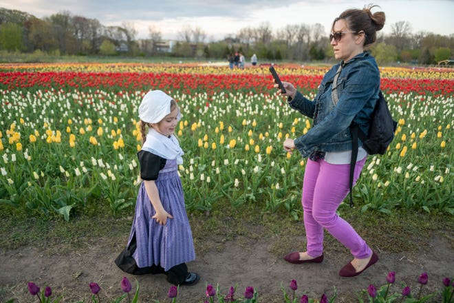 Dressed in traditional Dutch clothing, four-year-old Olivia Boone, of Holland, has her photograph taken by her mother Jessie as they walk through the tulip fields at Windmill Island Gardens park, in Holland, April 29, 2021.