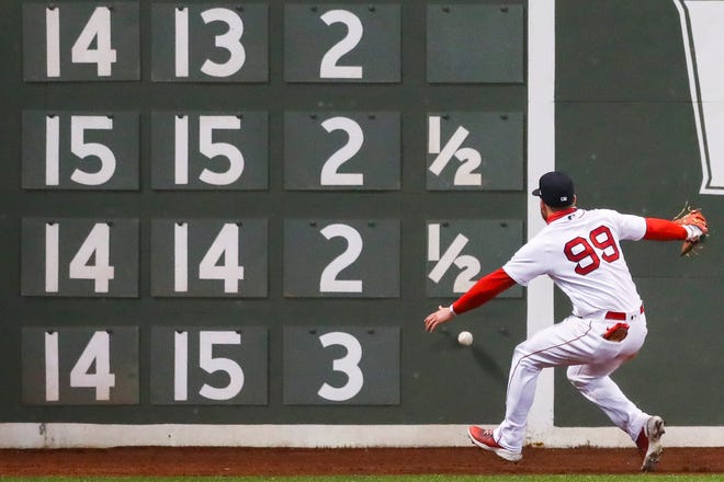 Alex Verdugo of the Boston Red Sox misplays a ball hit against the Green Monster scoreboard in the sixth inning of a game against the Detroit Tigers.