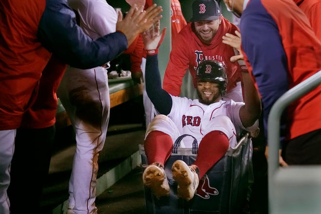 Boston Red Sox's Xander Bogaerts high-fives teammates while being pushed in a laundry cart through the dugout after his two-run home run against the Detroit Tigers during the second inning.