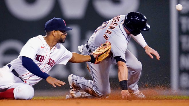 Detroit Tigers' Robbie Grossman, right, advances safely to second as the ball gets away from Boston Red Sox shortstop Xander Bogaerts, left, during the sixth inning.