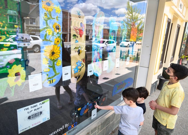 Faris Ghalayini, 5, Jude Ghalayini, 3 and Adnan Ghalayini, 10 look over the artwork in the window of Blake Team Realty in downtown Rochester.