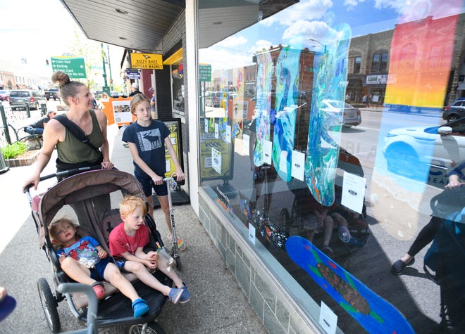 Jennifer Jones looks over the skateboard art with children Teddy Jones 3, Henry Jones, 4 and Andie Jones,12 during Deck Art 2021, downtown Rochester’s 11th annual skateboard art exhibition and competition displayed in stores and storefront windows of Rochester on May 13, 2021.