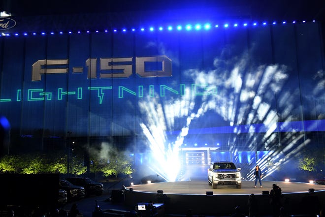Chief engineer of the Ford F-150 truck Linda Zhang talks about the F-150 Lightning electric pickup whose logo is projected on the side of Ford World Headquarters in Dearborn on May 19, 2021.