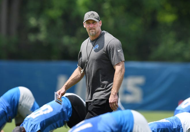 Detroit Lions head coach Dan Campbell watches over his players during stretching exercises at minicamp.