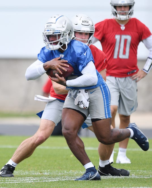 Lions running back D'Andre Swift takes the handoff from quarterback Tim Boyle during drills.
