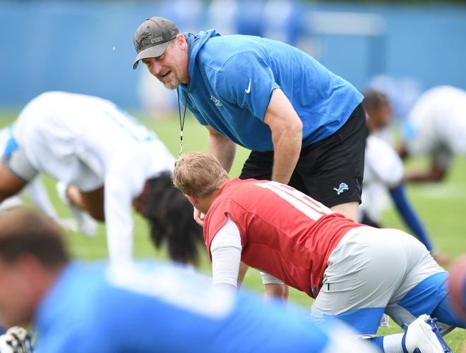 Lions head coach Dan Campbell talks with quarterback Jared Goff during stretching at the start of practice.