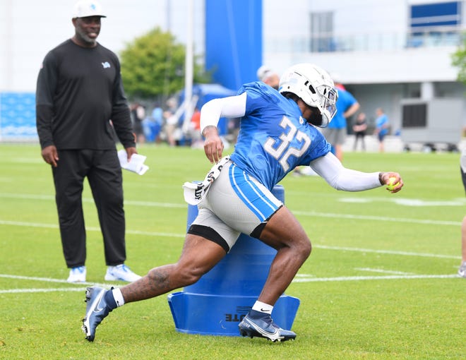 Lions offensive coordinator Anthony Lynn watches running back D'Andre Swift during drills.