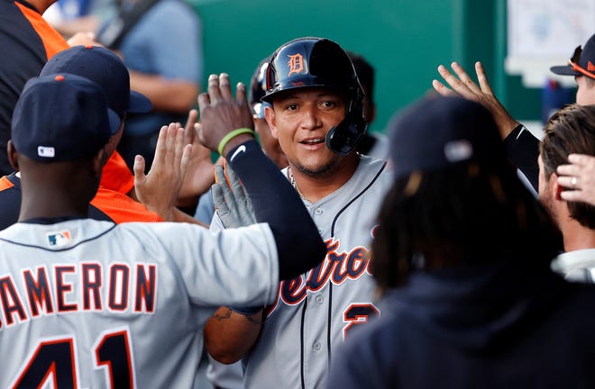 Tiger Miguel Cabrera is congratulated by teammates in the dugout after scoring during the 1st inning of the game.