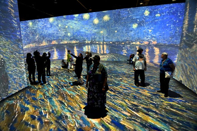 People walk through the immersive gallery at the Beyond Van Gogh exhibit during the first public day with more than 300 iconic artworks at the TCF Center in Detroit on Friday, June 25, 2021. Beyond Van Gogh uses cutting-edge projection technology to create an engaging journey into the world of Van Gogh.