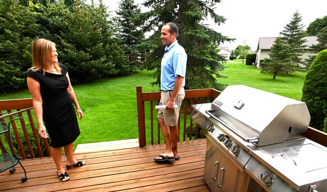 Sine and Monaghan Real Estate agent Danielle Boulier, left, of St. Clair Twp., shows off the rear deck to this Boulder Creek Condo in East China Twp., to Todd Carlson, of Clinton Twp., Thursday afternoon, July 15, 2021.