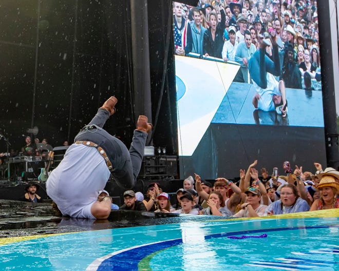 Chris Lane slips and falls on the rain soaked stage during the Faster Horses music festival on July 16, 2021, in Brooklyn.