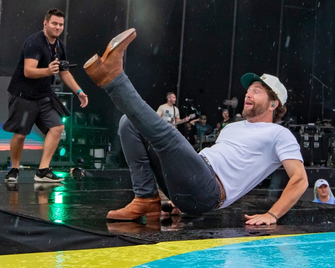 Chris Lane slips and falls on the rain soaked stage during the Faster Horses music festival on July 16, 2021, in Brooklyn.