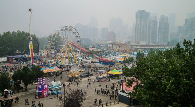 Smoke from wildfires is carried by winds, obscuring the view for visitors to the Calgary Stampede in Calgary, Alberta, Sunday, July 18, 2021.