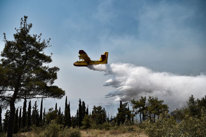 TOPSHOT - A Canadair aircarft drops water on a forest fire at the Thessaloniki Seih Sou park, which overlooks the city of Thessaloniki, on July 13, 2021. - The risk of new fires was considered high, after several days of hot temperatures across most of Greece. (Photo by Sakis MITROLIDIS / AFP) (Photo by SAKIS MITROLIDIS/AFP via Getty Images)