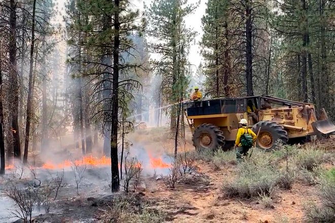 In this photo provided by the Bootleg Fire Incident Command, firefighters battle the Bootleg Fire in southern Oregon, Saturday, July 17, 2021. Meteorologists predicted critically dangerous fire weather through at least Monday with lightning possible in both California and southern Oregon.