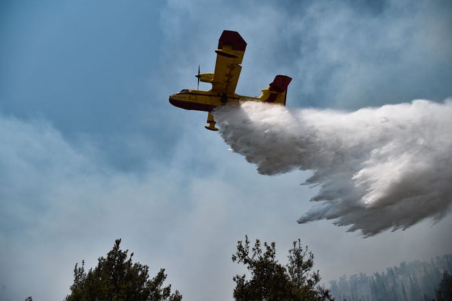 A Canadair aircraft drops water on a forest fire at the Thessaloniki Seih Sou park, which overlooks the city of Thessaloniki, on July 13, 2021. - The risk of new fires was considered high, after several days of hot temperatures across most of Greece. (Photo by Sakis MITROLIDIS / AFP) (Photo by SAKIS MITROLIDIS/AFP via Getty Images)