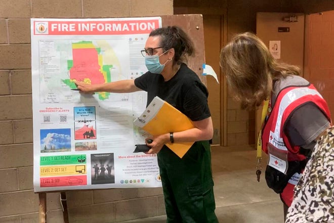 In this photo provided by the Bootleg Fire Incident Command, a public information officer talks with evacuees at a Red Cross Shelter near the Bootleg Fire in southern Oregon, Sunday, July 18, 2021. The destructive Bootleg Fire, one of the largest in modern Oregon history, has already burned more than 476 square miles (1,210 square kilometers), an area about the size of Los Angeles. Meteorologists predicted critically dangerous fire weather through at least Monday with lightning possible in both California and southern Oregon.