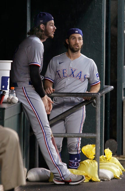 Texas Rangers catcher Jonah Heim, left, waits with teammate Charlie Culberson during a rain delay before their game.