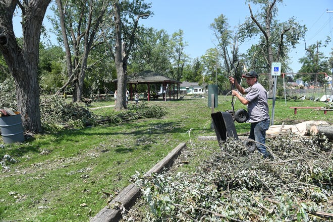 Volunteer Paul Ambrosiewicz, 30, of Armada Township piles up tree debris at the Village of Armada Memorial Park.  A mix of volunteers and work crews clean up the area after Saturday's tornado in Armada, Michigan, on July 26, 2021.