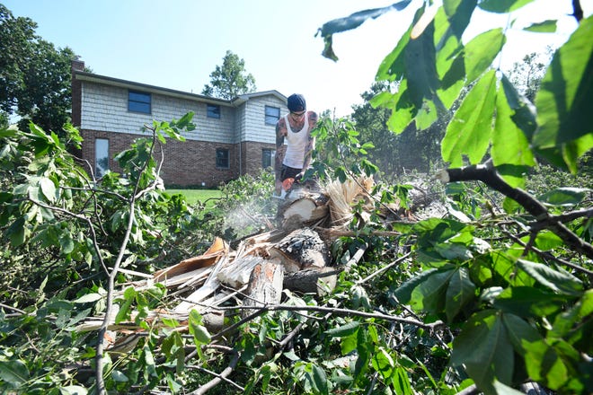 Kyle MacMichael of A Cut Above cuts and clears away branches from a downed tree due to a tornado Saturday in White Lake Township, Michigan, on July 26, 2021.