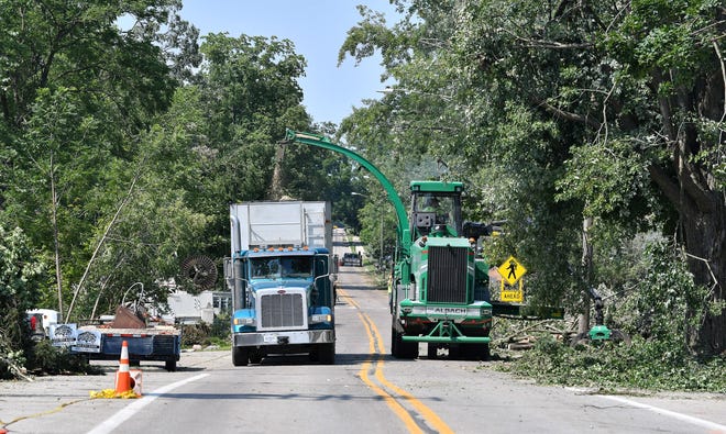 Tree debris is mulched on North Fulton Street.  A mix of volunteers and work crews clean up the area after Saturday's tornado in Armada, Michigan, on July 26, 2021.