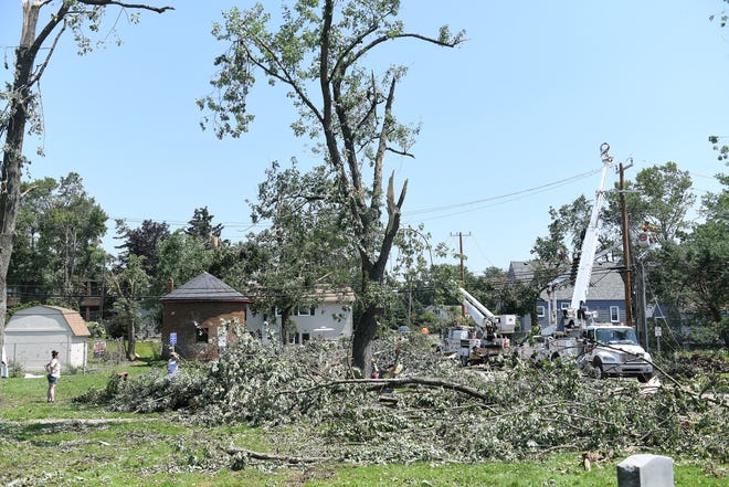 Huge trees are broken apart at the Village of Armada Memorial Park. A mix of volunteers and work crews clean up the area after Saturday's tornado in Armada, Michigan, on July 26, 2021.