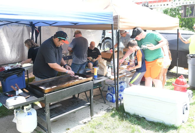 Volunteer Alex Abraham of Armada, left, cooks up food donated by Armade in MI and Burgher Family Farm for volunteers and crews involved in the cleanup.  A mix of volunteers and work crews clean up the area after Saturday's tornado in Armada, Mich. on July 26, 2021.