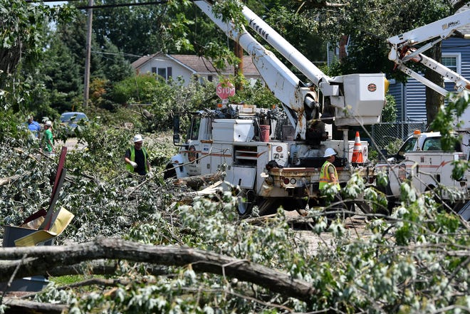 Crews from Xtreme Powerline Construction work to restore power where a new pole has been installed near North Fulton Street. A mix of volunteers and work crews clean up the area after Saturday's tornado in Armada, Michigan, on July 26, 2021.