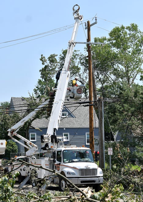 A worker from Xtreme Powerline Construction works to restore power where a new pole has been installed near North Fulton Street. A mix of volunteers and work crews clean up the area after Saturday's tornado in Armada, Michigan, on July 26, 2021.