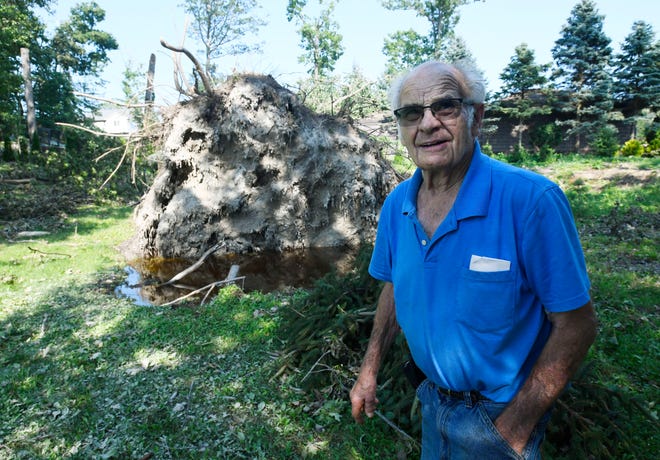 Joe Laflamme walks past the roots of a huge downed tree in White Lake Township, Michigan, on July 26, 2021. The tree , toppled by a tornado Saturday, fell on the property next to his and branches landed on his fencing and some of his out buildings.