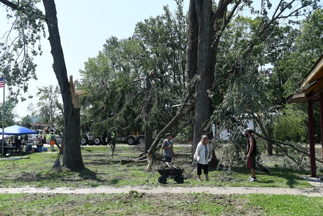 Volunteers help clean up the tree debris at the Village of Armada Memorial Park.  A mix of volunteers and work crews clean up the area after Saturday's tornado in Armada, Michigan, on July 26, 2021.