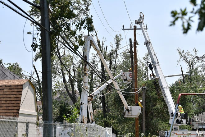 A worker from Xtreme Powerline Construction works to restore power where a new pole has been installed near North Fulton Street and Village of Armada Memorial Park.  A mix of volunteers and work crews clean up the area after Saturday's tornado in Armada, Michigan, on July 26, 2021.
