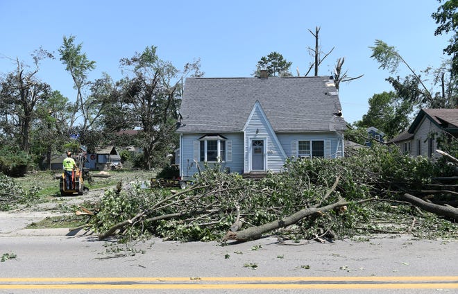Tree debris is moved from around this home on North Fulton Street. A mix of volunteers and work crews clean up the area after Saturday's tornado in Armada, Michigan, on July 26, 2021.