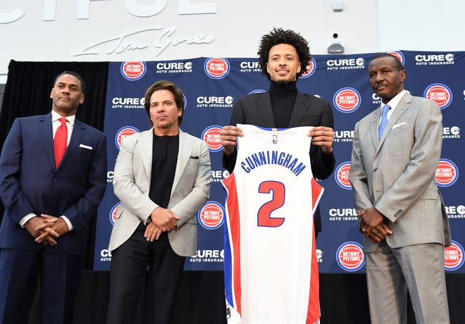 Cade Cunningham holds his new jersey with l-r, Troy Weaver, General Manager, Tom Gores, owner and Dwane Casey, head coach.