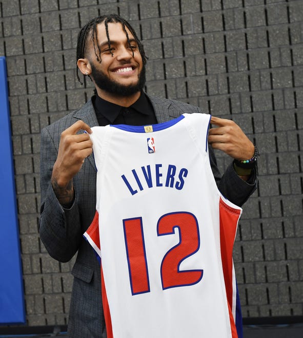Isaiah Livers holds up his new jersey after the Pistons press conference.