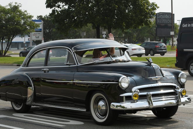 Dean McKean of Warren waves hi to onlookers near the corner of Gratiot and 15 Mile, as he drives his 1950 Chevy during the 18th annual Clinton Township Gratiot Cruise, Sunday, Aug. 1, 2021 in Clinton Township, Mich.